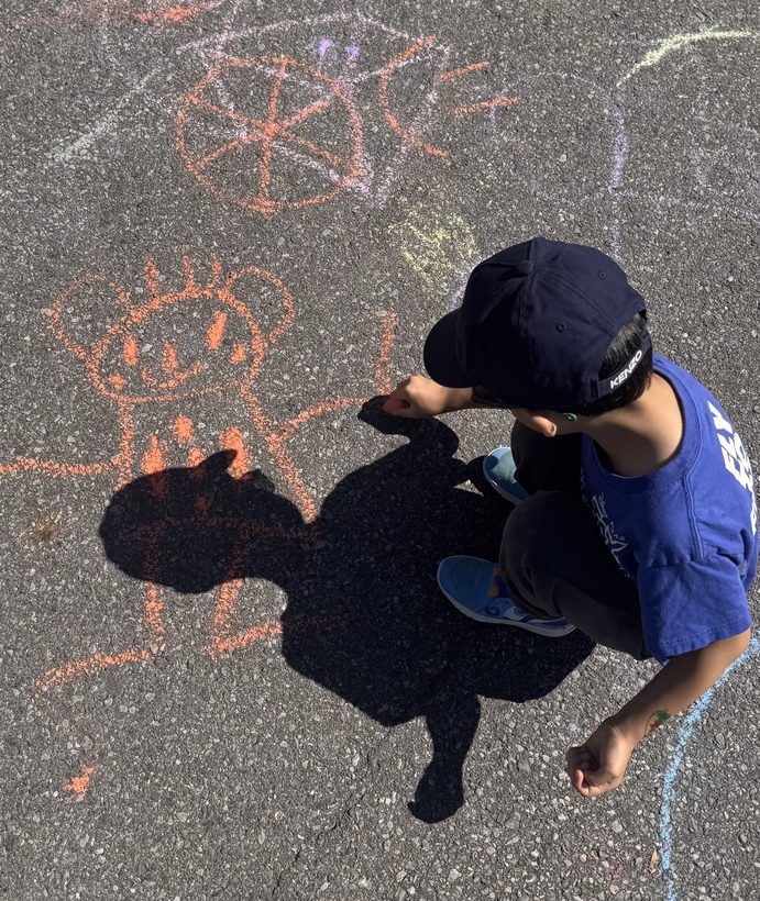 Aiden crouched on the driveway, drawing the little guy in orange chalk